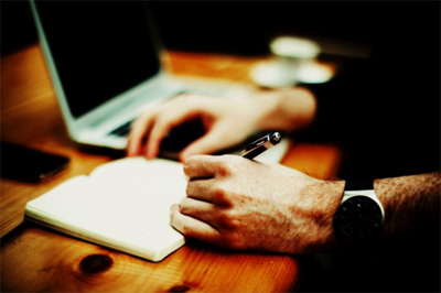 Milwaukee digital forensic investigations Man's hand, taking notes by a laptop